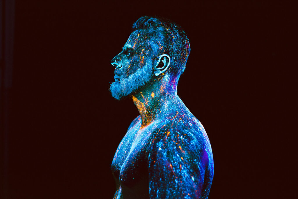 Mann mit ultravioletten Puder in schillernden Neon-Farben